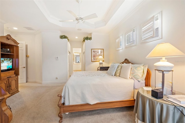 carpeted bedroom with ornamental molding, ensuite bath, ceiling fan, and a raised ceiling