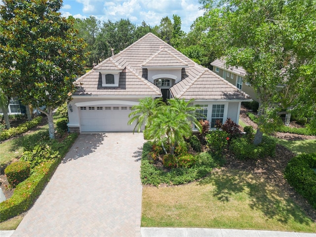 view of front of property with a garage, a front lawn, decorative driveway, and stucco siding