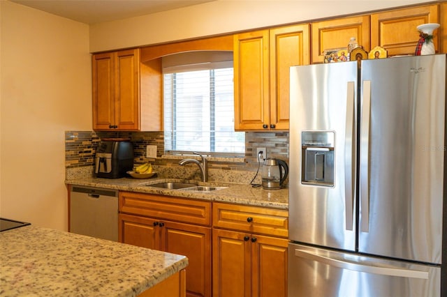 kitchen featuring backsplash, stainless steel appliances, light stone counters, and sink