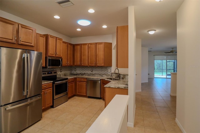 kitchen featuring appliances with stainless steel finishes, backsplash, sink, light tile flooring, and ceiling fan