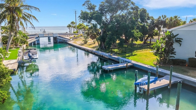 view of swimming pool with a lawn, a water view, and a dock