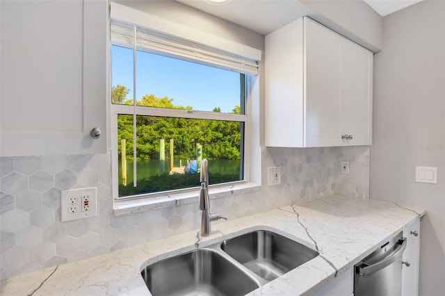 kitchen featuring decorative backsplash, light stone countertops, sink, dishwasher, and white cabinets