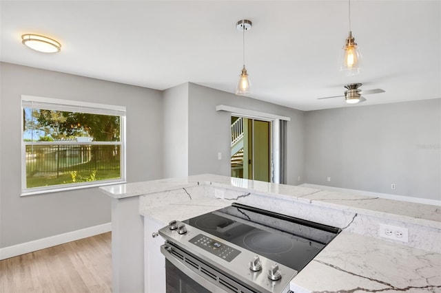 kitchen featuring electric range, ceiling fan, light stone countertops, decorative light fixtures, and light hardwood / wood-style floors