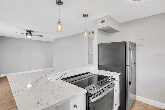 kitchen with light stone countertops, stainless steel appliances, ceiling fan, pendant lighting, and light hardwood / wood-style flooring