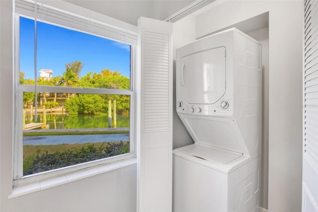 laundry room featuring stacked washer / drying machine and a water view