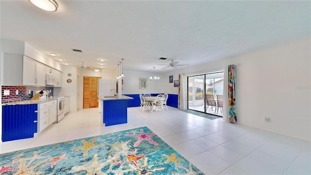 kitchen with white appliances, a kitchen island with sink, ceiling fan, tasteful backsplash, and white cabinetry