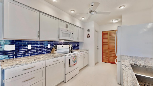 kitchen with decorative backsplash, white cabinets, light stone countertops, and white appliances