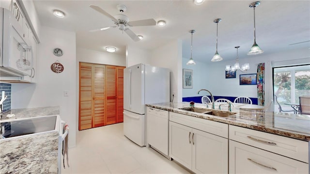 kitchen featuring light stone countertops, white appliances, sink, decorative light fixtures, and white cabinetry