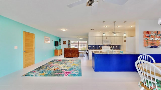 kitchen featuring white appliances, backsplash, decorative light fixtures, light stone counters, and white cabinetry