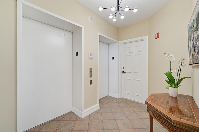 entryway with elevator, light tile flooring, and a chandelier