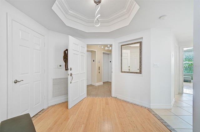 hall featuring light tile flooring, a raised ceiling, and crown molding