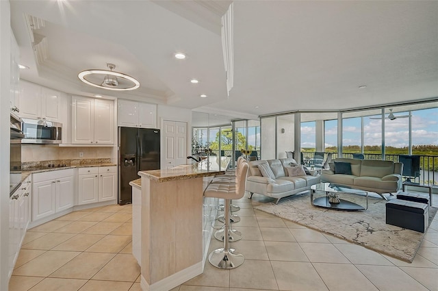 kitchen featuring floor to ceiling windows, black fridge, and white cabinetry