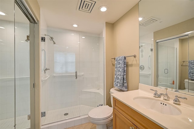 bathroom with tile flooring, vanity, toilet, and a shower with shower door