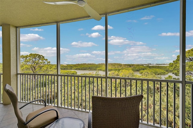 unfurnished sunroom featuring a water view, a wealth of natural light, and ceiling fan