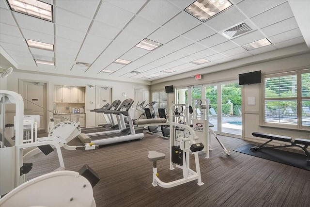 exercise room featuring a drop ceiling and dark carpet