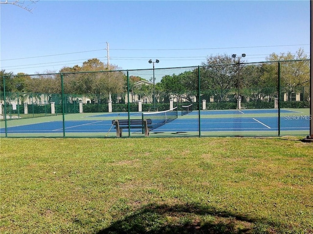 view of tennis court featuring a lawn