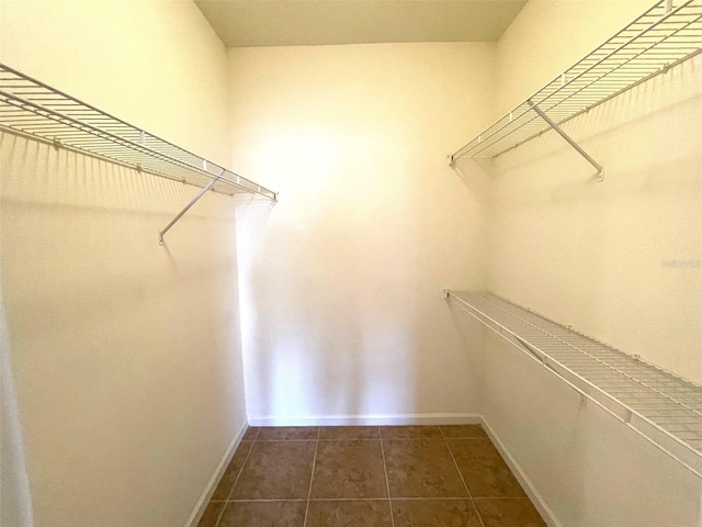 walk in closet with dark tile patterned flooring