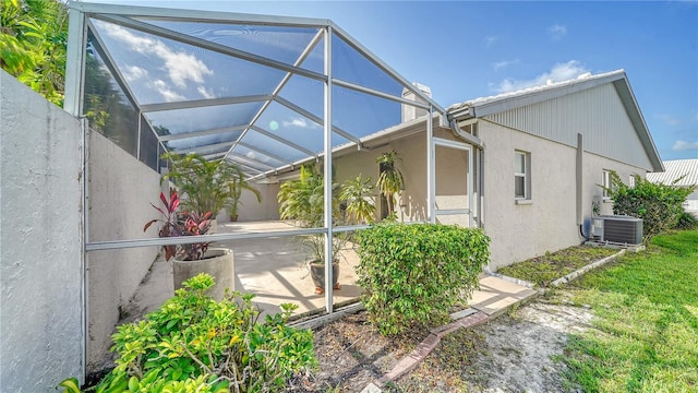 view of property exterior with glass enclosure and central AC unit