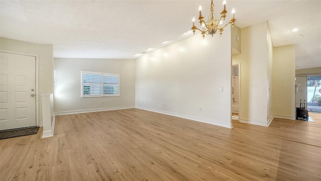 empty room featuring light wood-type flooring, an inviting chandelier, and lofted ceiling