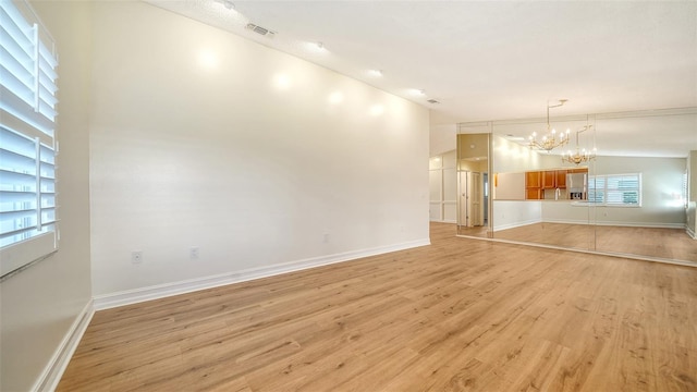 unfurnished living room featuring light hardwood / wood-style flooring, lofted ceiling, and a notable chandelier