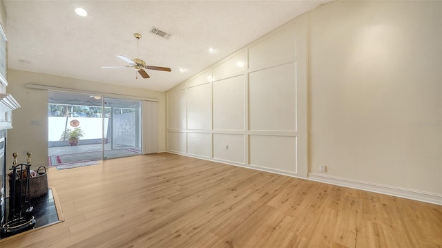 unfurnished living room with a textured ceiling, vaulted ceiling, light hardwood / wood-style flooring, and ceiling fan