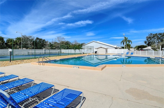 view of swimming pool featuring tennis court