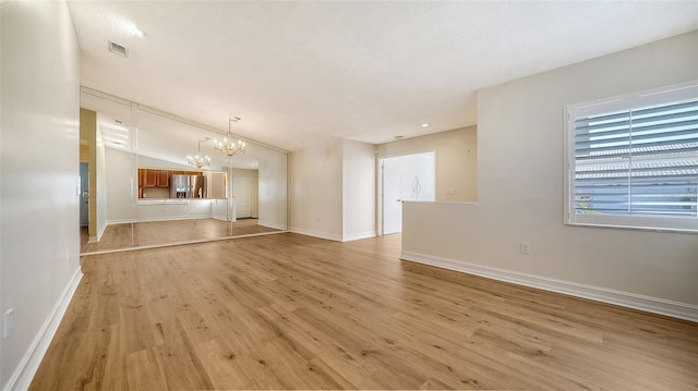 unfurnished living room featuring a chandelier, light wood-type flooring, and lofted ceiling