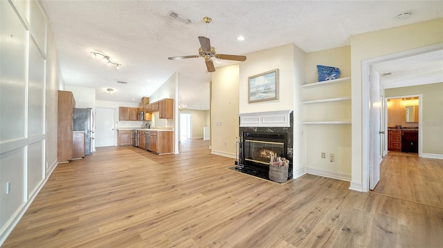 unfurnished living room with a premium fireplace, a textured ceiling, and light wood-type flooring