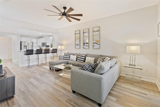 living room featuring ceiling fan and light hardwood / wood-style flooring