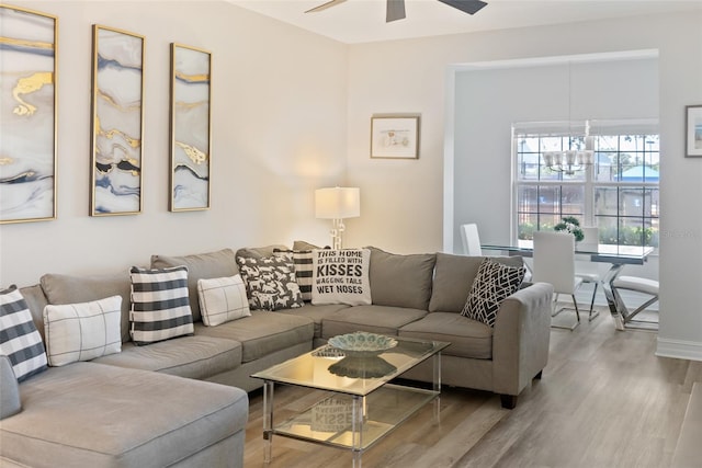 living room with ceiling fan with notable chandelier and light hardwood / wood-style flooring