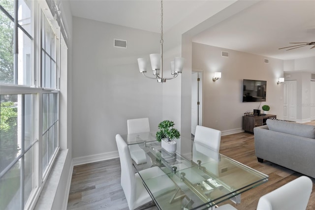 dining space featuring ceiling fan with notable chandelier and hardwood / wood-style floors