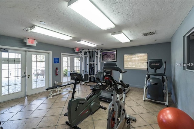 exercise room featuring a textured ceiling, light tile patterned floors, and french doors