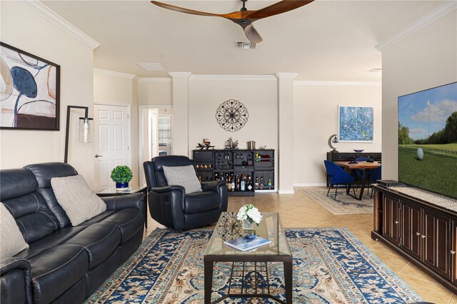 tiled living room with decorative columns, ceiling fan, and ornamental molding