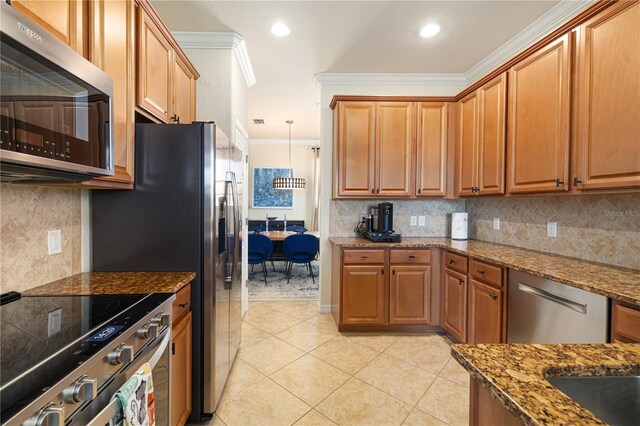 kitchen with stainless steel appliances, tasteful backsplash, dark stone countertops, light tile floors, and ornamental molding