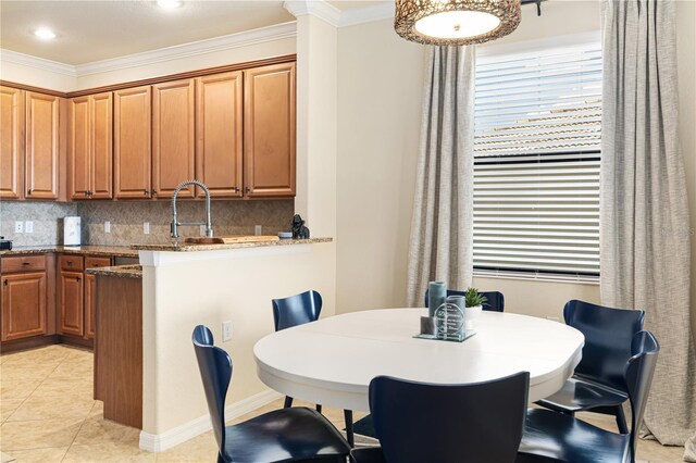 dining room with sink, crown molding, and light tile floors