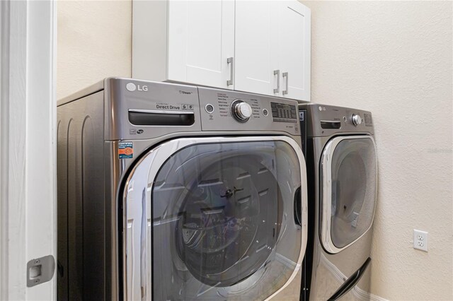 clothes washing area featuring cabinets and washer and dryer