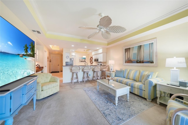 carpeted living room featuring a raised ceiling, ceiling fan, and crown molding