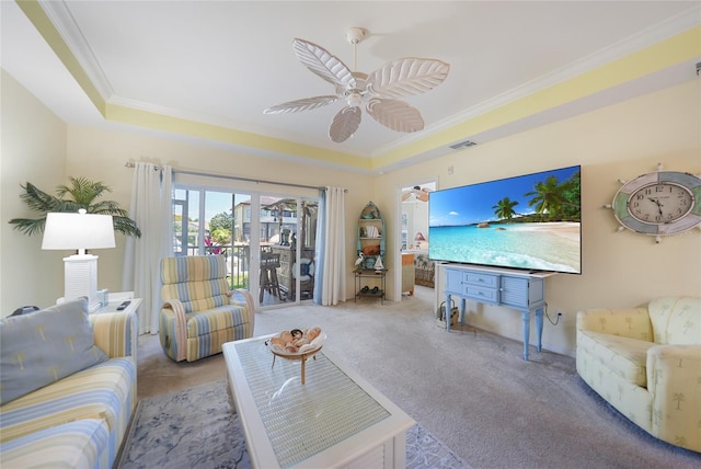 carpeted living room featuring a tray ceiling, ornamental molding, and ceiling fan