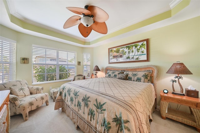 bedroom with ceiling fan, carpet, ornamental molding, and a tray ceiling