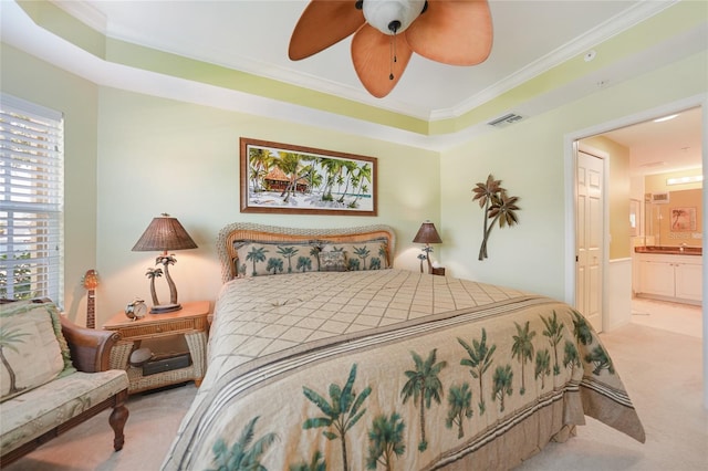 bedroom with a tray ceiling, ceiling fan, crown molding, ensuite bath, and carpet floors