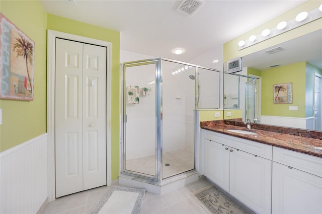 bathroom with tile floors, vanity with extensive cabinet space, and a shower with shower door