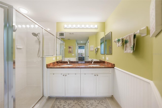 bathroom with double vanity, a shower with door, and tile flooring