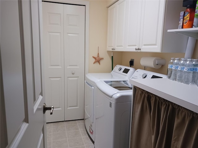 laundry room with washer and clothes dryer, light tile flooring, electric dryer hookup, and cabinets