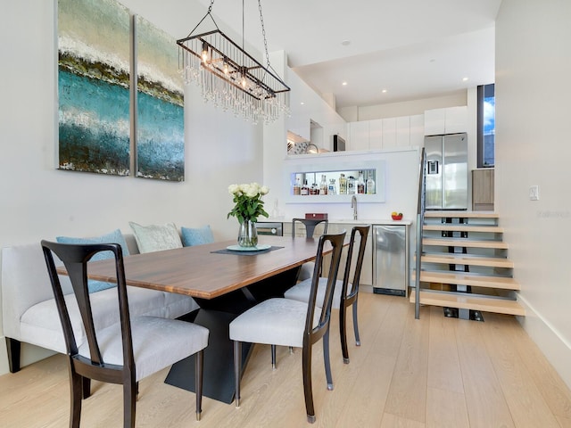 dining area with sink, a chandelier, and light wood-type flooring