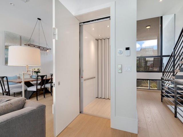 corridor with light hardwood / wood-style floors and elevator