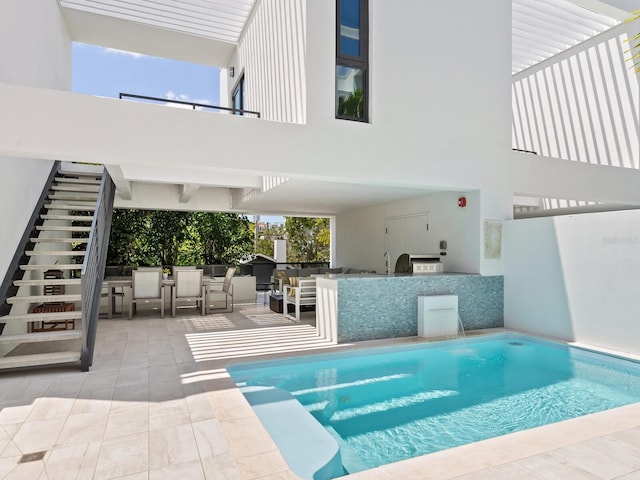 view of swimming pool featuring an outdoor bar, an outdoor kitchen, and a patio