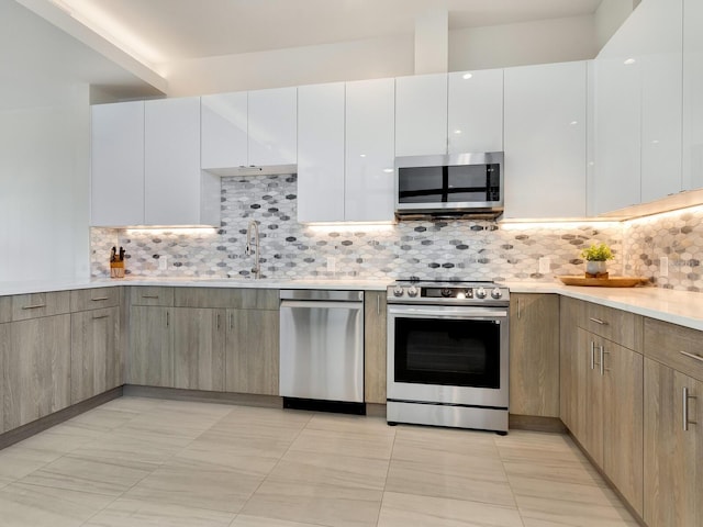 kitchen with backsplash, white cabinetry, light tile patterned flooring, and appliances with stainless steel finishes