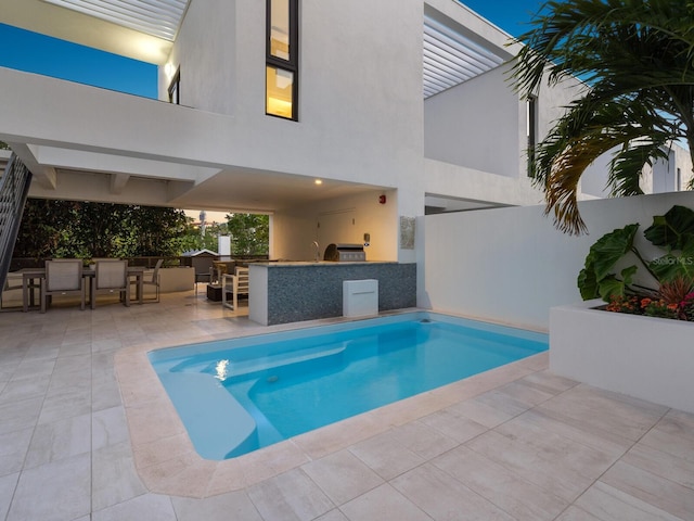 view of pool featuring an outdoor kitchen, a patio area, and exterior bar