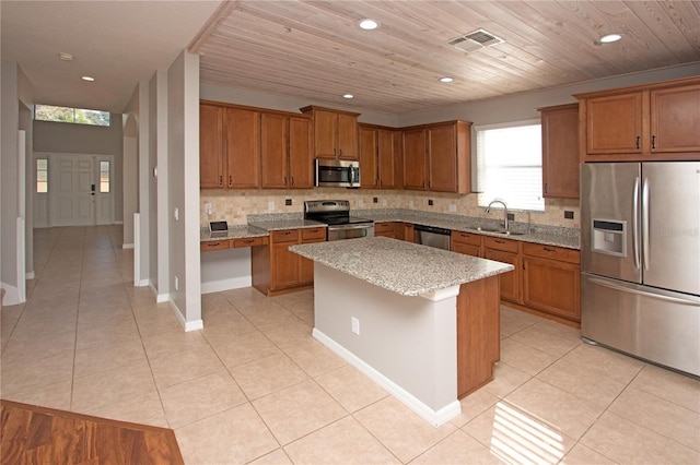 kitchen with sink, backsplash, a center island, light tile patterned floors, and stainless steel appliances