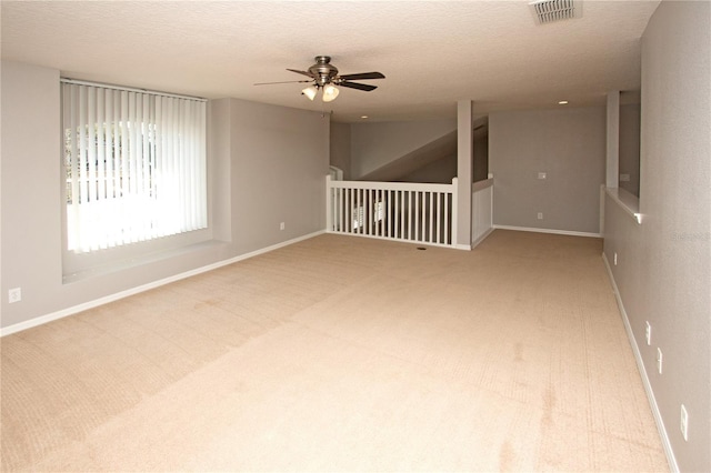 carpeted spare room with a textured ceiling and ceiling fan